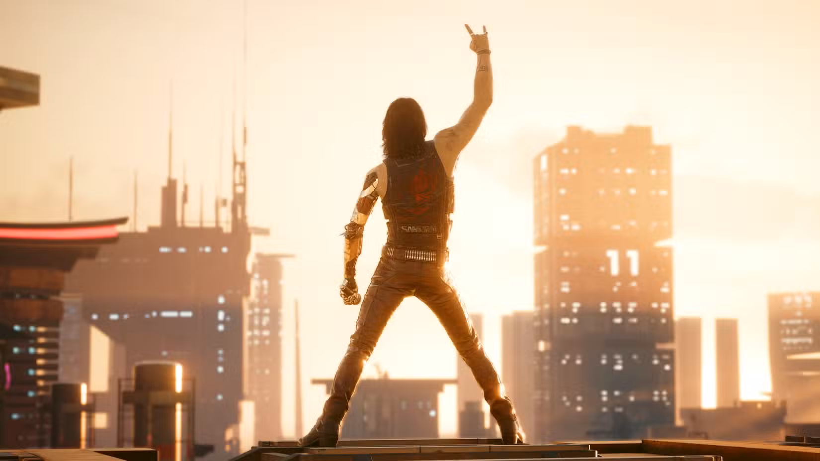 Keanu Reeves, as Johnny Silverhand, makes a devil hand gesture while looking at the Night City skyline in Cyberpunk 2077.