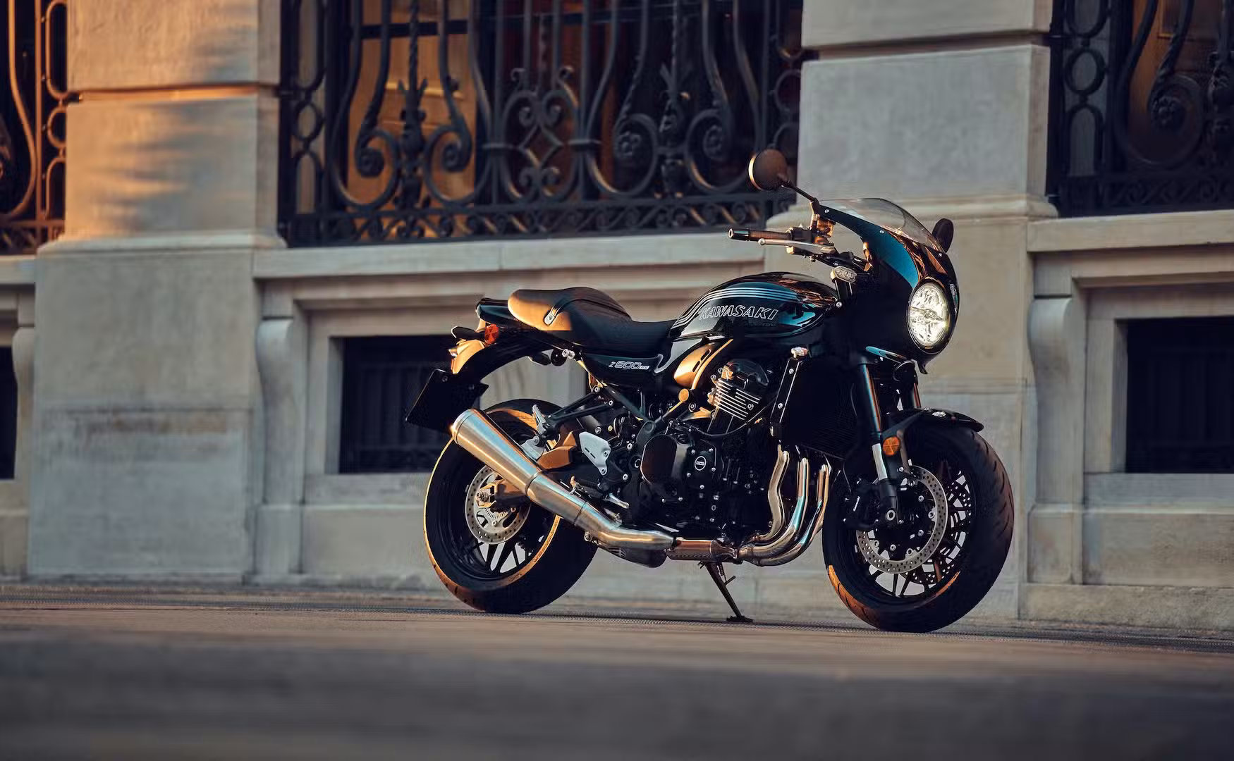 Low angle static shot of a black and green Kawasaki Z900RS Cafe parked in front of a building with old-style architecture