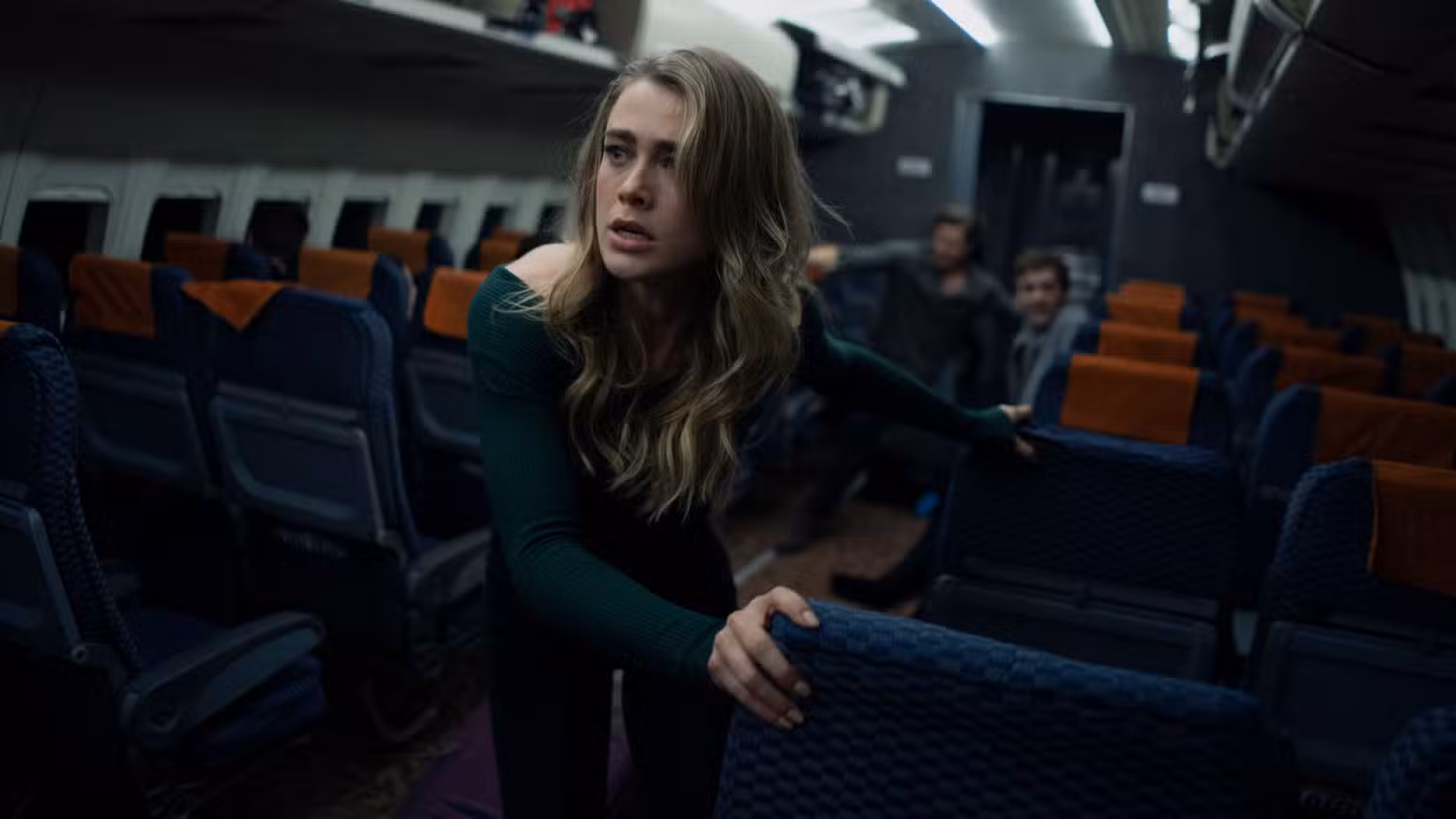 Melissa Roxburgh as Michaela Stone struggling to climb through a plane aisle in Manifest.