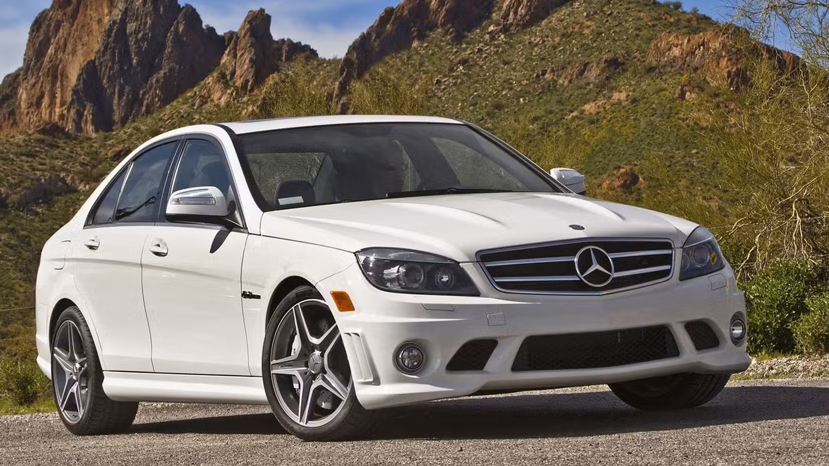 Front and side shot of a white Mercedes-Benz C63 AMG parked on a road