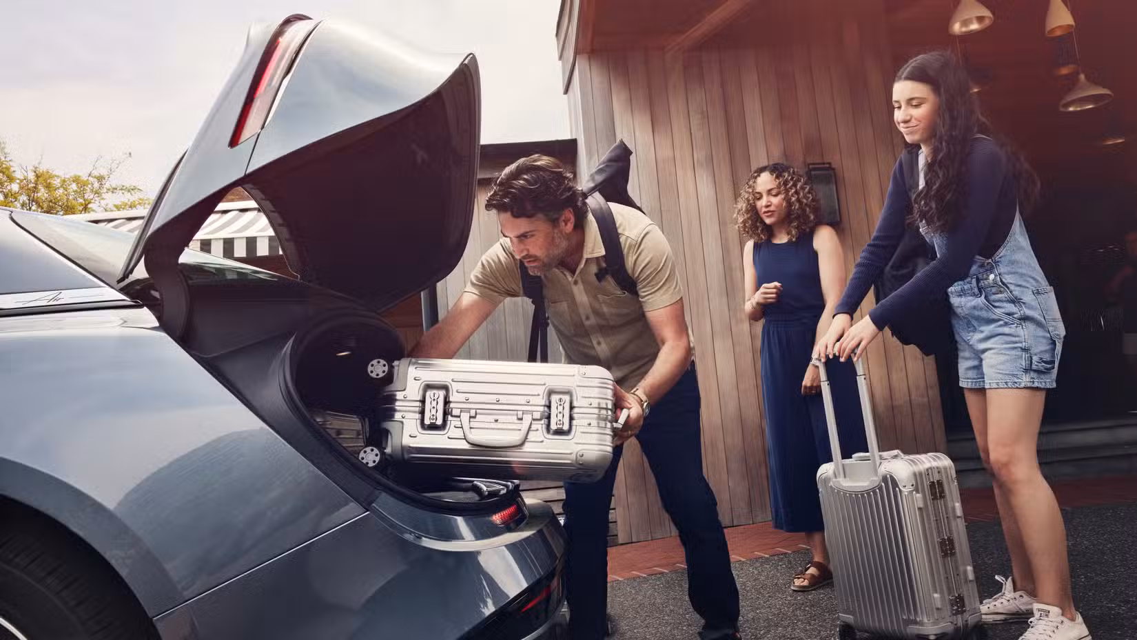 Side shot of a family loading luggage into the Lucid Air Pure RWD trunk