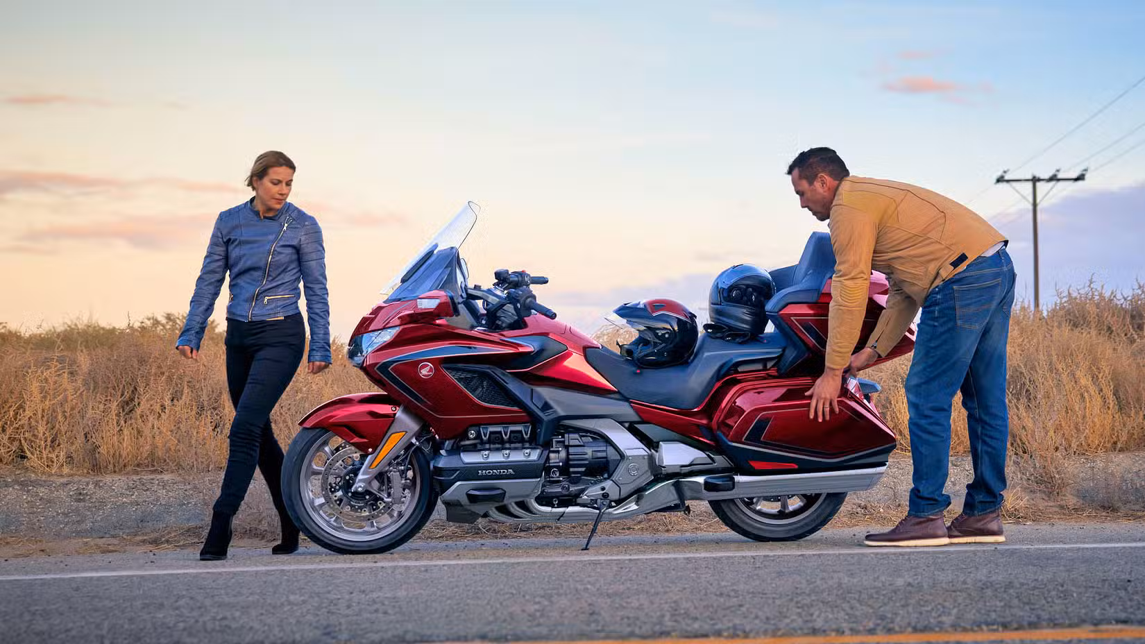 Rider and passenger next to a red 2026 Honda Gold Wing Tour parked roadside