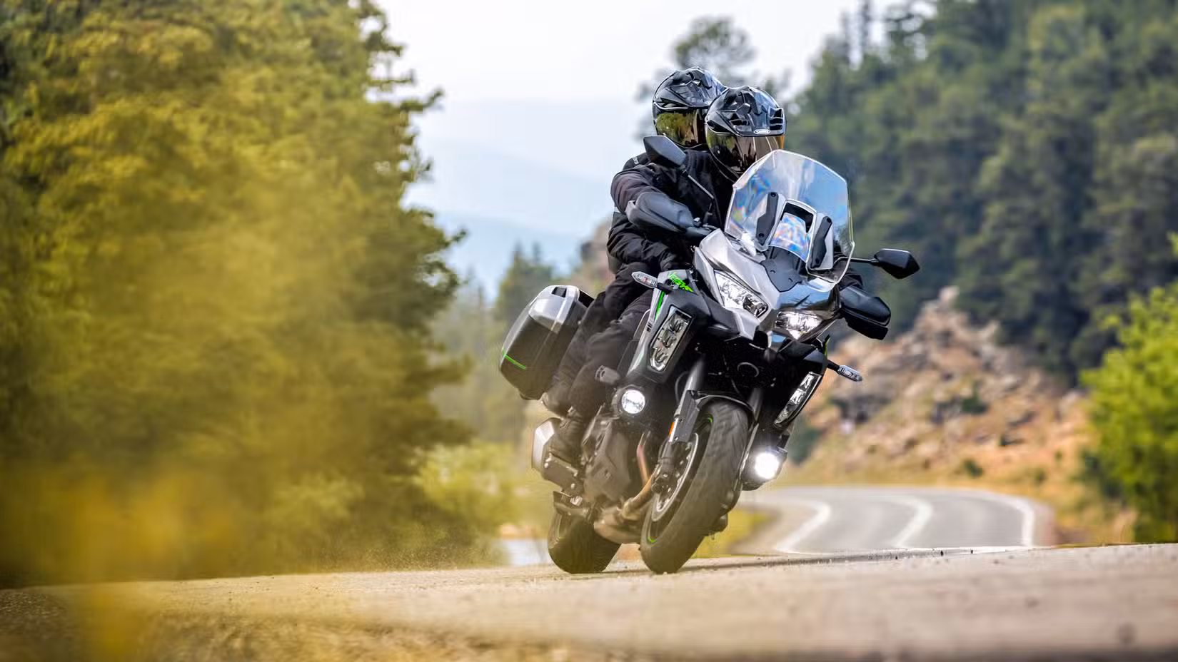Rider and passenger on a 2025 Kawasaki Versys 1100 SE LT navigating a curve