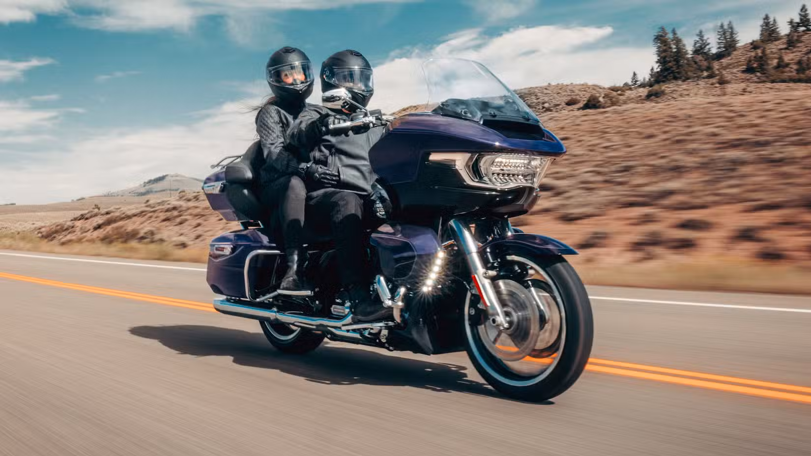 Rider and pillion on a 2026 Harley-Davidson Road Glide Limited cruising on the highway
