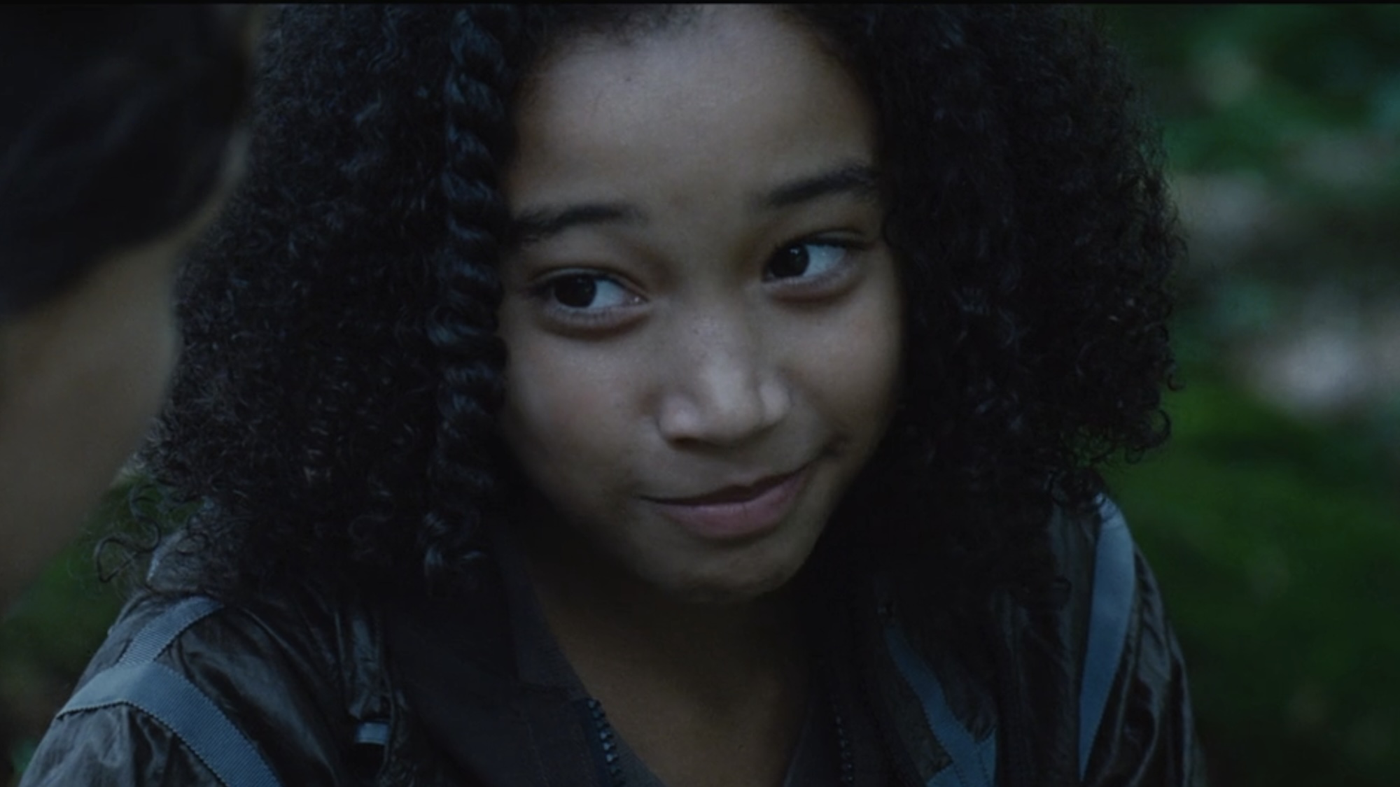 Rue smiling talking to Katniss about Peeta in The Hunger Games.