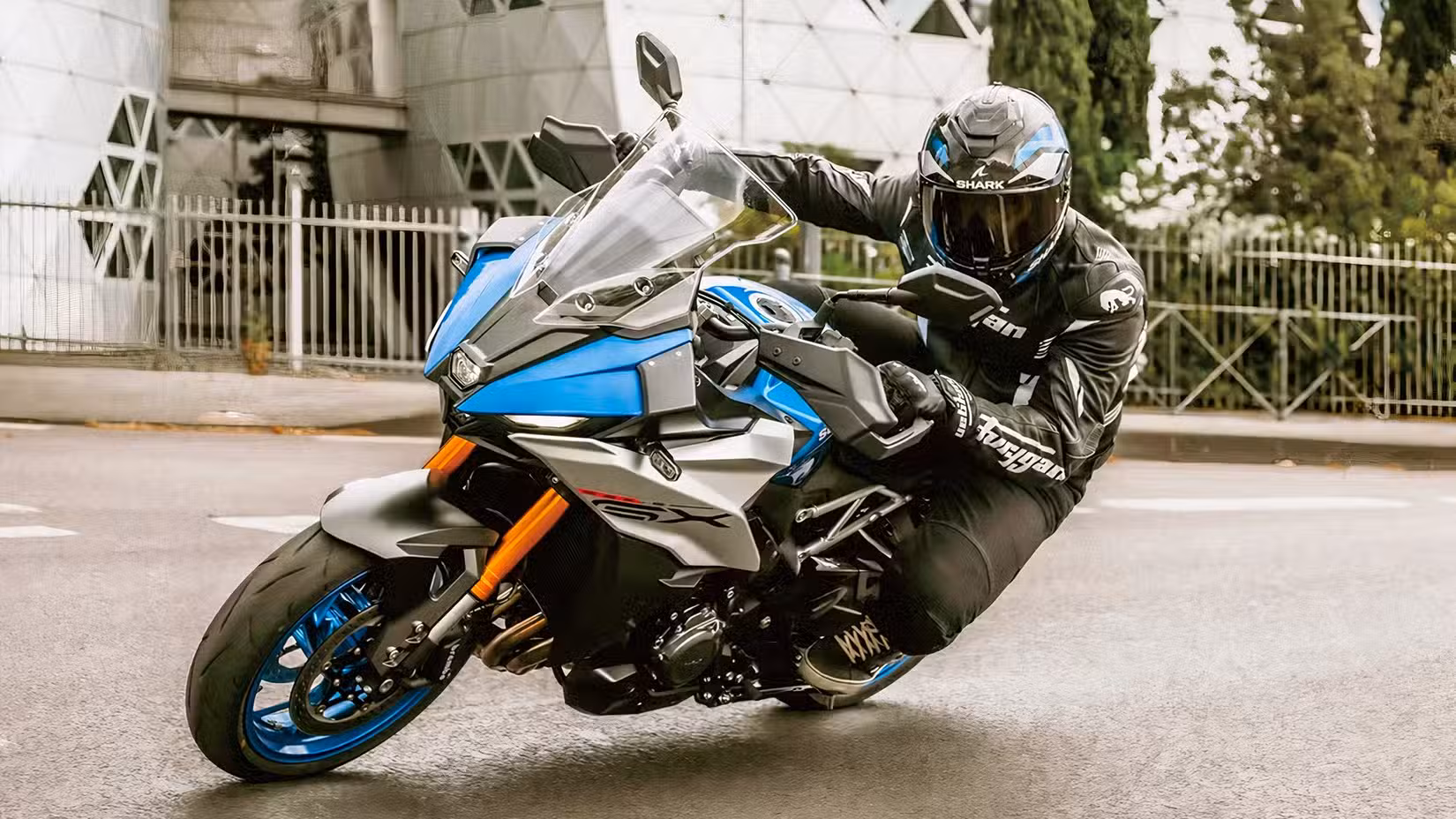 Action Shot of Suzuki GSX-S1000GX+ cornering in city streets.