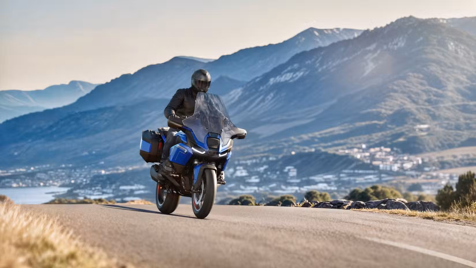 Front shot of a 2026 BMW R 1300 RT driving in front of mountain range