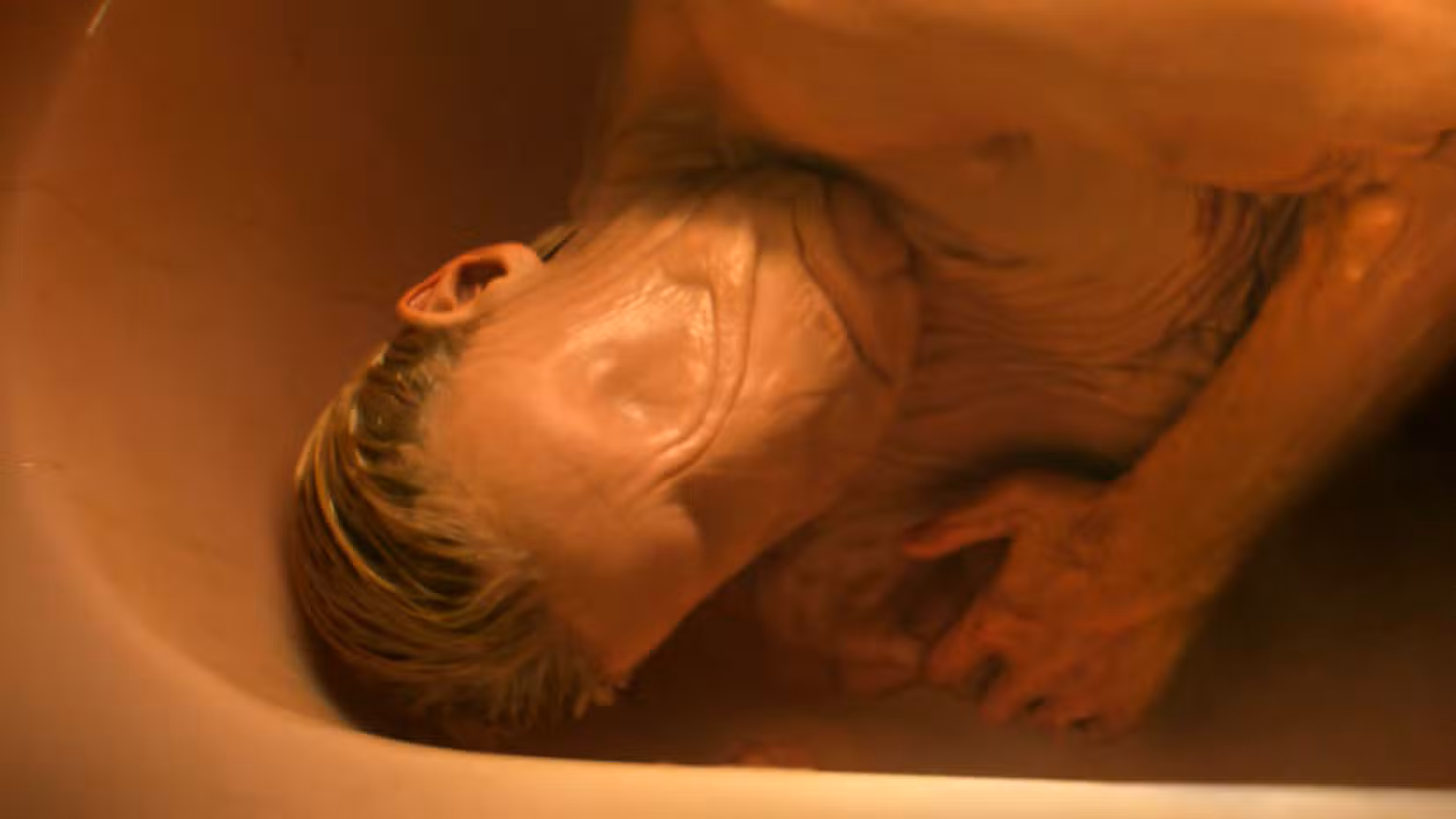 Tom Rhys Harries as Matt Hagen lying in a tub with his skin smoothed out in Clayface