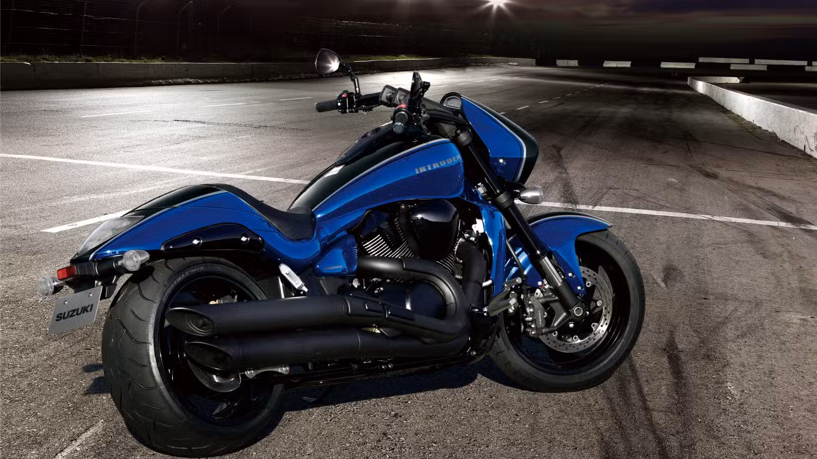 Static rear right three quarter shot of a  blue and black Suzuki Boulevard M109R at night
