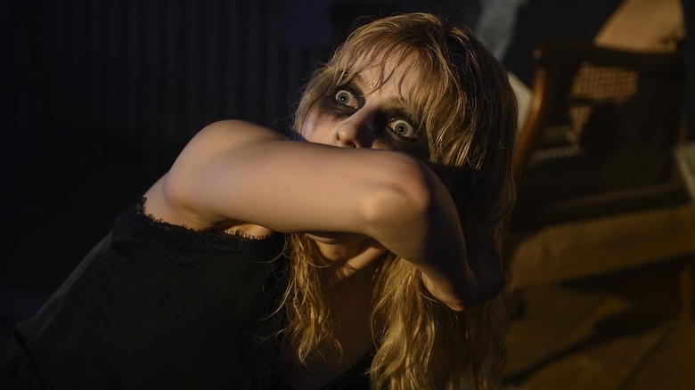 Ellie, with blonde hair and running mascara around her eyes, looking up in horror in Last Night in Soho