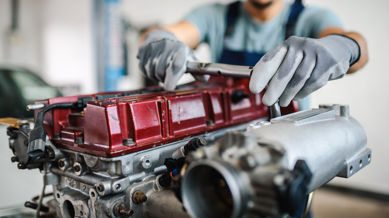 A mechanic working on an engine that has been removed from a car