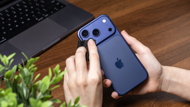 Person cleaning iPhone 17 camera lens.